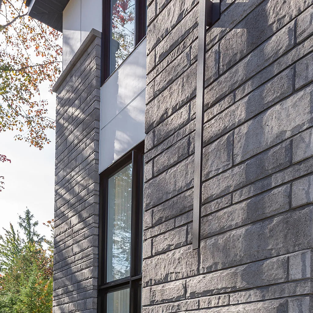 Pierre de béton grise avec texture légèrement ciselée, utilisée pour revêtement de façade.