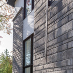 Pierre de béton grise avec texture légèrement ciselée, utilisée pour revêtement de façade.
