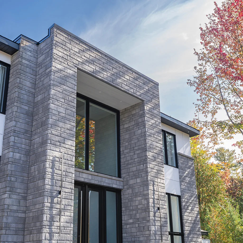 Pierre de béton grise avec texture légèrement ciselée, utilisée pour revêtement de façade.