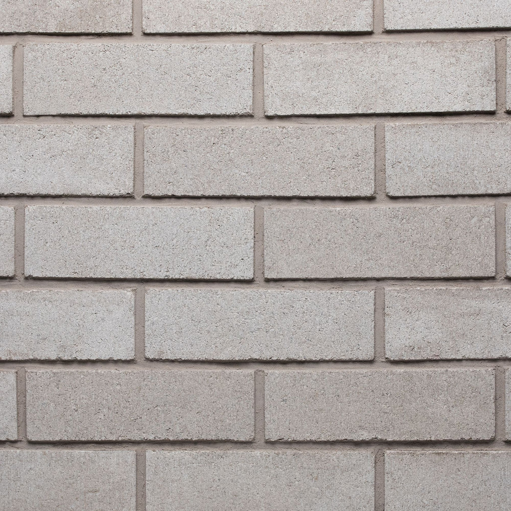 Mur en briques grises, texture lisse, disposées en rangées régulières, avec des joints clairs entre chaque brique.