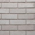 Mur en briques grises, texture lisse, disposées en rangées régulières, avec des joints clairs entre chaque brique.