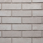 Mur en briques grises, texture lisse, disposées en rangées régulières, avec des joints clairs entre chaque brique.