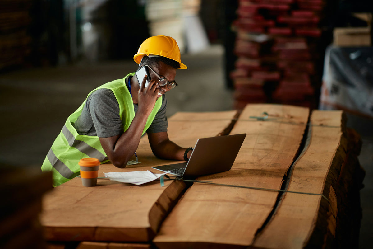 Homme casque jaune et gilet reflechissant avec ordinateur portable sur chantier.