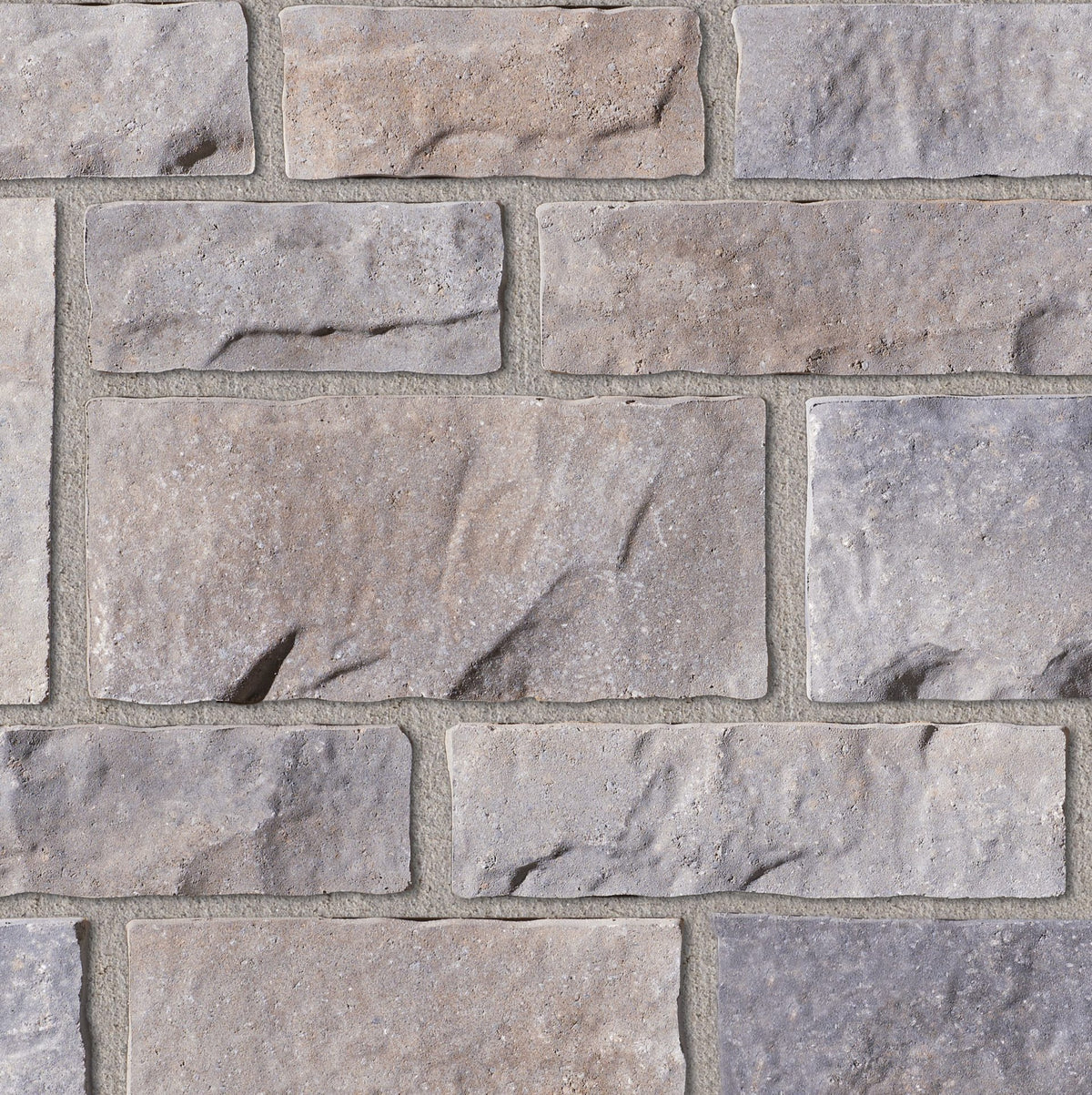 Mur en pierre avec des blocs de couleur grise et beige, présentant des textures variées et des joints de mortier.