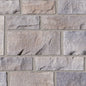 Mur en pierre avec des blocs de couleur grise et beige, présentant des textures variées et des joints de mortier.