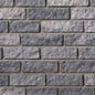 Mur de briques en pierre grise, avec des textures et des nuances variées, disposées en motifs rectangulaires.