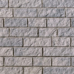 Mur en briques grises avec une texture rugueuse, disposées en rangées régulières.