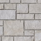 Mur en pierre de couleur beige clair avec des blocs de différentes tailles et textures, créant un motif naturel.