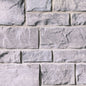Mur en pierre grise avec des blocs de différentes tailles et textures, créant un motif naturel et robuste.