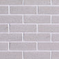 Mur de briques grises avec une texture lisse, disposées en rangées régulières.