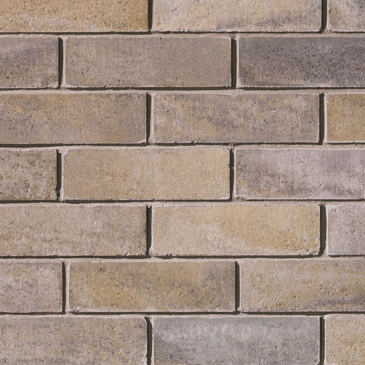 Mur de briques en béton dans des teintes de beige et gris, avec des joints visibles entre les briques.