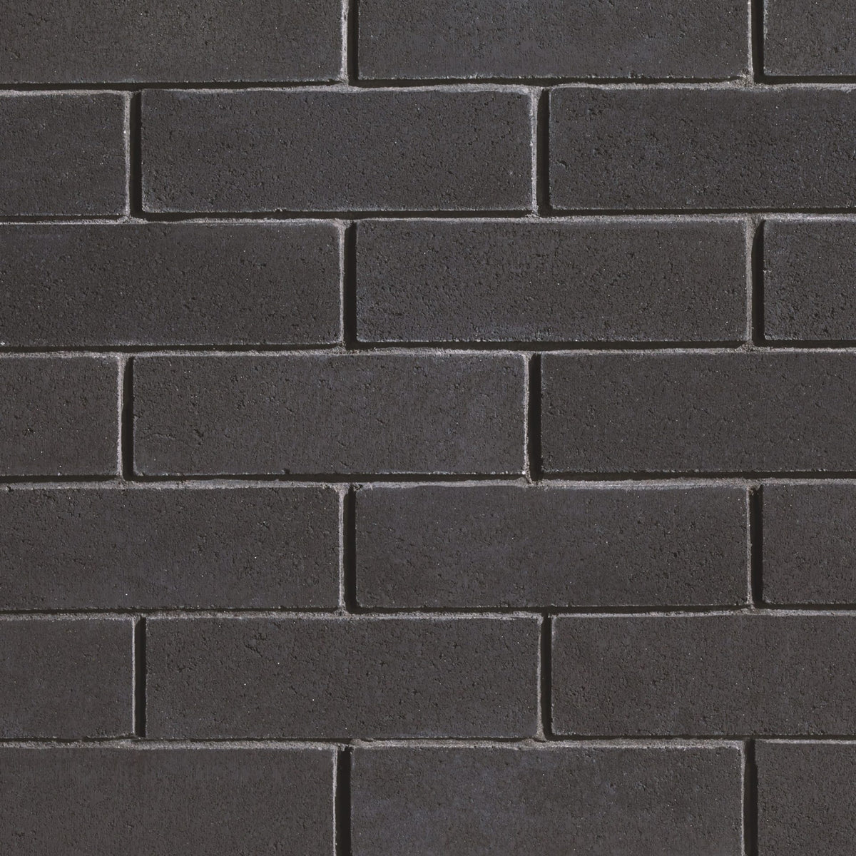 Briques noires en béton disposées en motif de maçonnerie, surface lisse et uniforme.