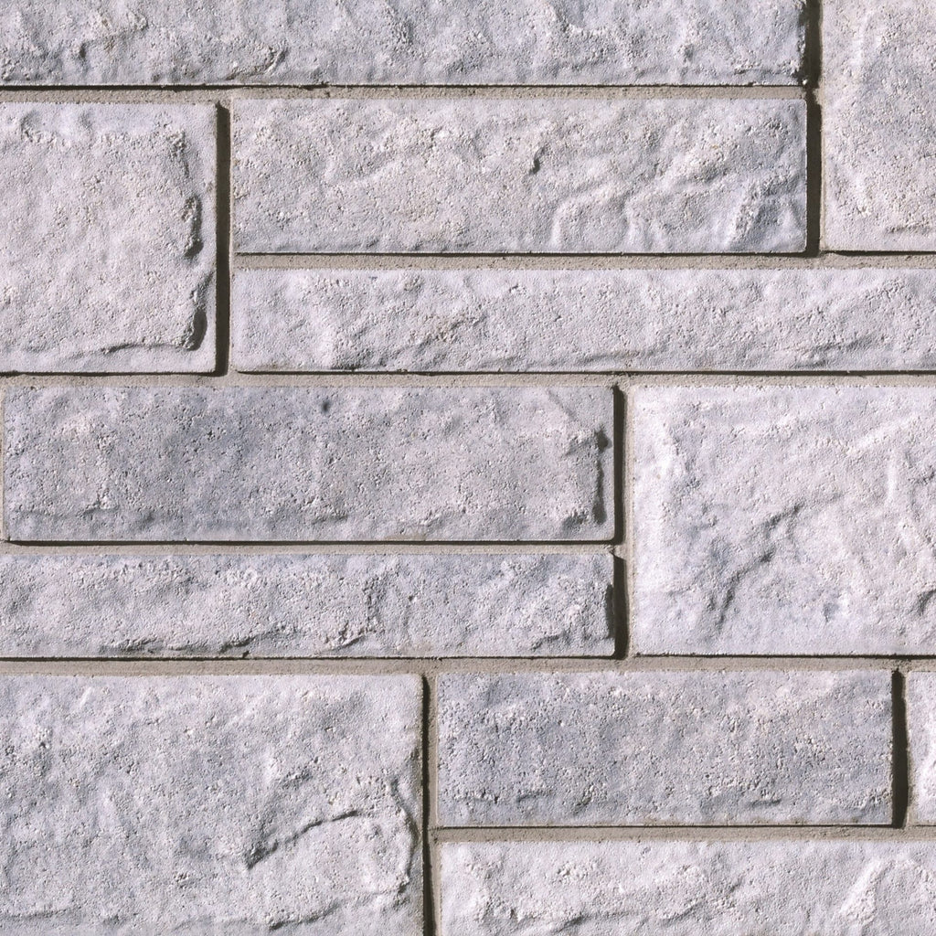 Mur en briques de béton gris clair avec une texture rugueuse et des joints visibles entre les blocs.