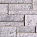 Mur en briques de béton gris clair avec une texture rugueuse et des joints visibles entre les blocs.