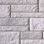 Mur en briques de béton gris clair avec une texture rugueuse et des joints visibles entre les blocs.