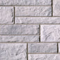 Mur en briques de béton gris clair avec une texture rugueuse et des joints visibles entre les blocs.