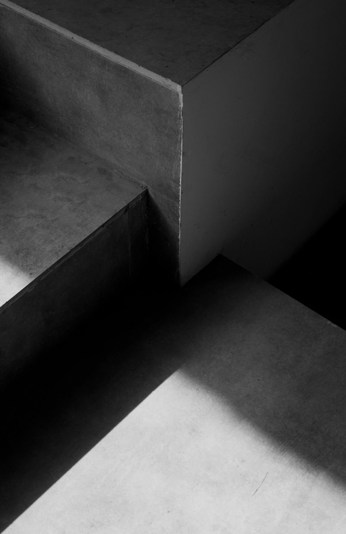 Concrete staircase with sharp angles, contrasting lighting creating shadows on the steps.