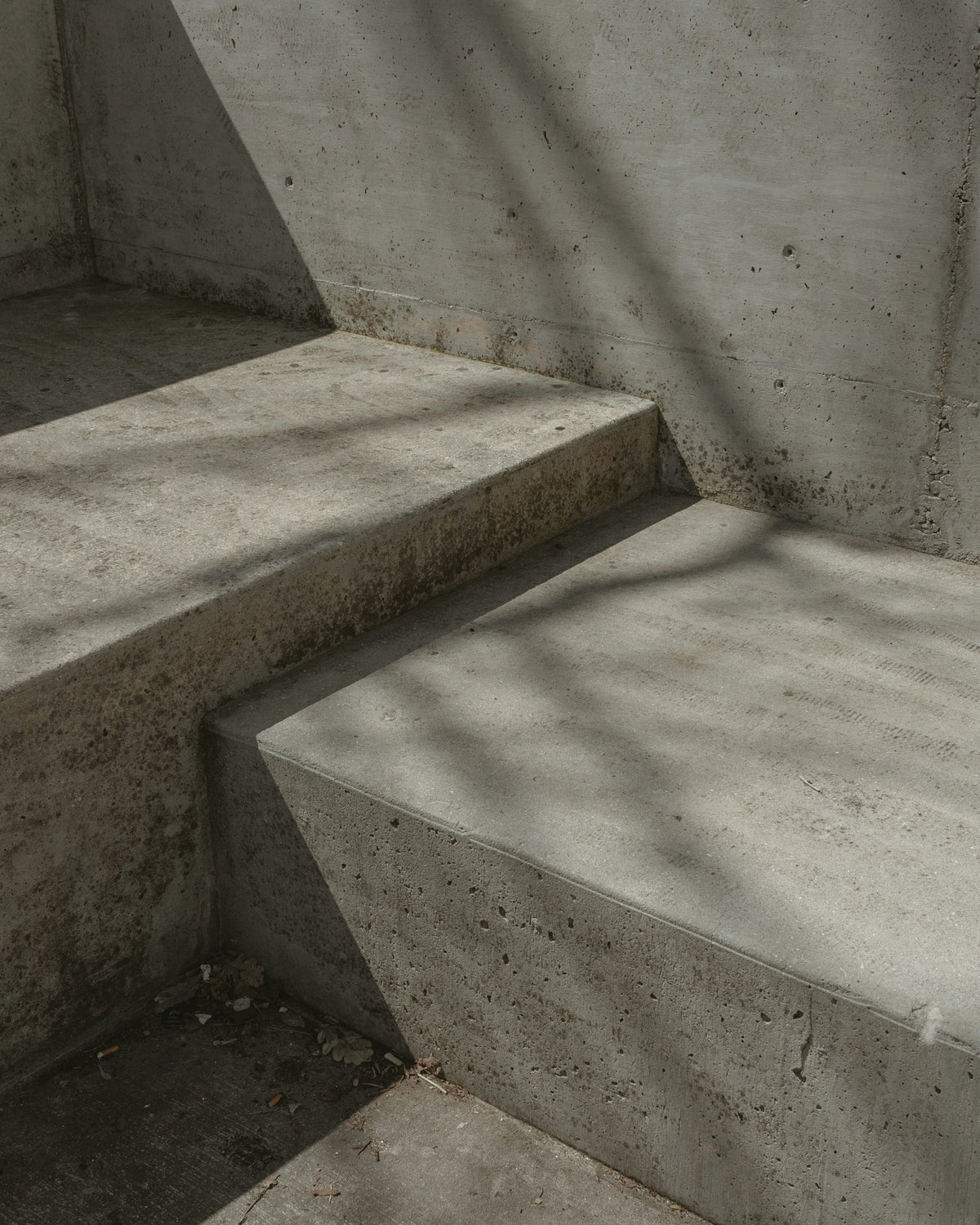 Escalier en béton avec des ombres projetées, surface rugueuse et angles nets, ambiance minimaliste.